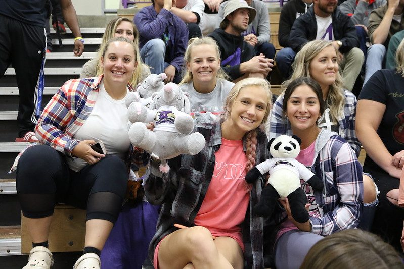 Crowd of students sitting in the Mabee Fieldhouse stands holding stuffed animals