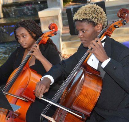 Two Avila cellos players perform outside Blasco Hall