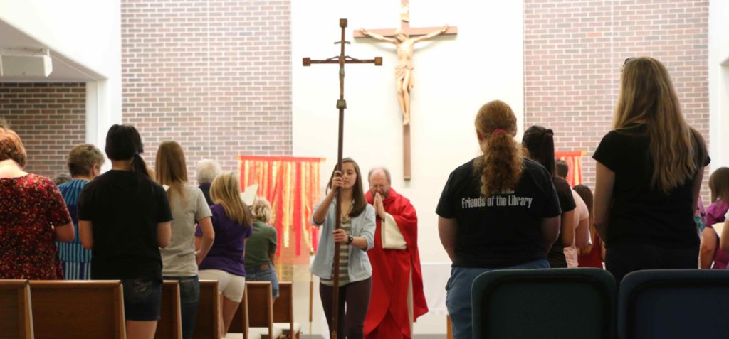 Student leading Father Keith Branson down the isle inside the Foyle Hall chapel