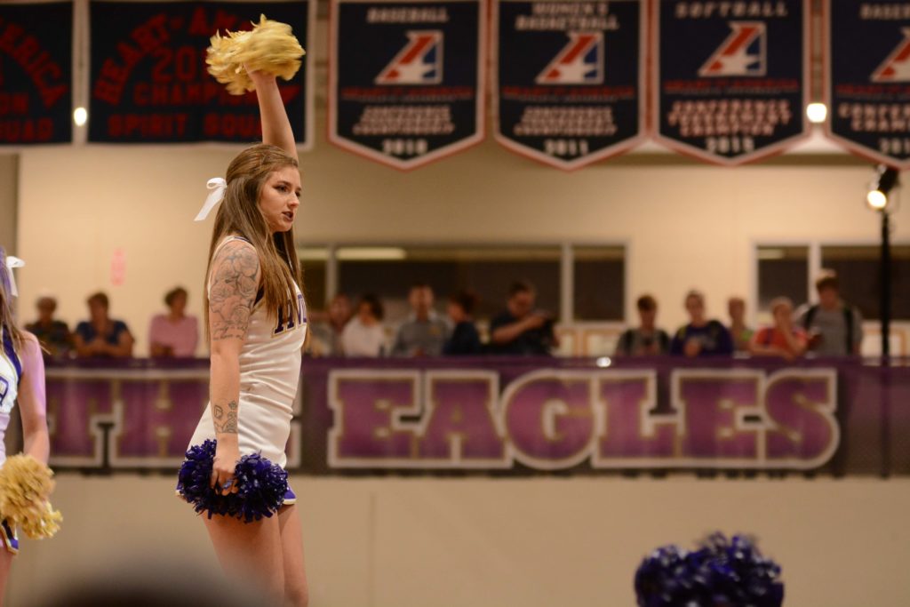 Close up of a cheerleader with poms inside Mabee Fieldhouse