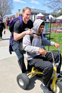两个学生在校园狂欢节上骑着一辆巨大的三轮车
