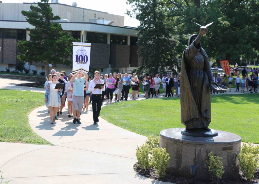 The Avila community marches across campus together in a long line promoting peace.