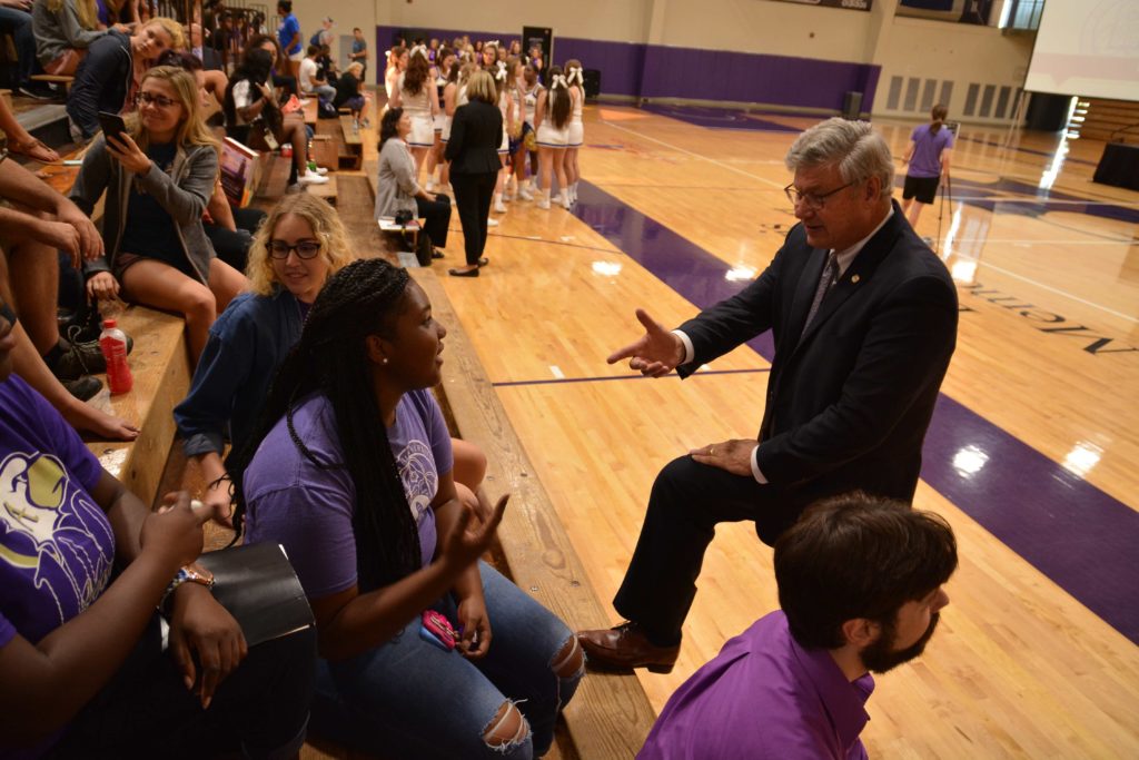 President Ronald Slepitza talks with students on the bleachers of Mabee Fieldhouse