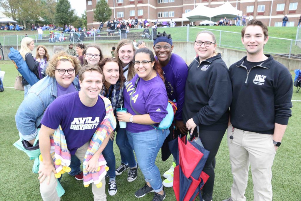 A group of students pose for the camera while standing on the football sidelines