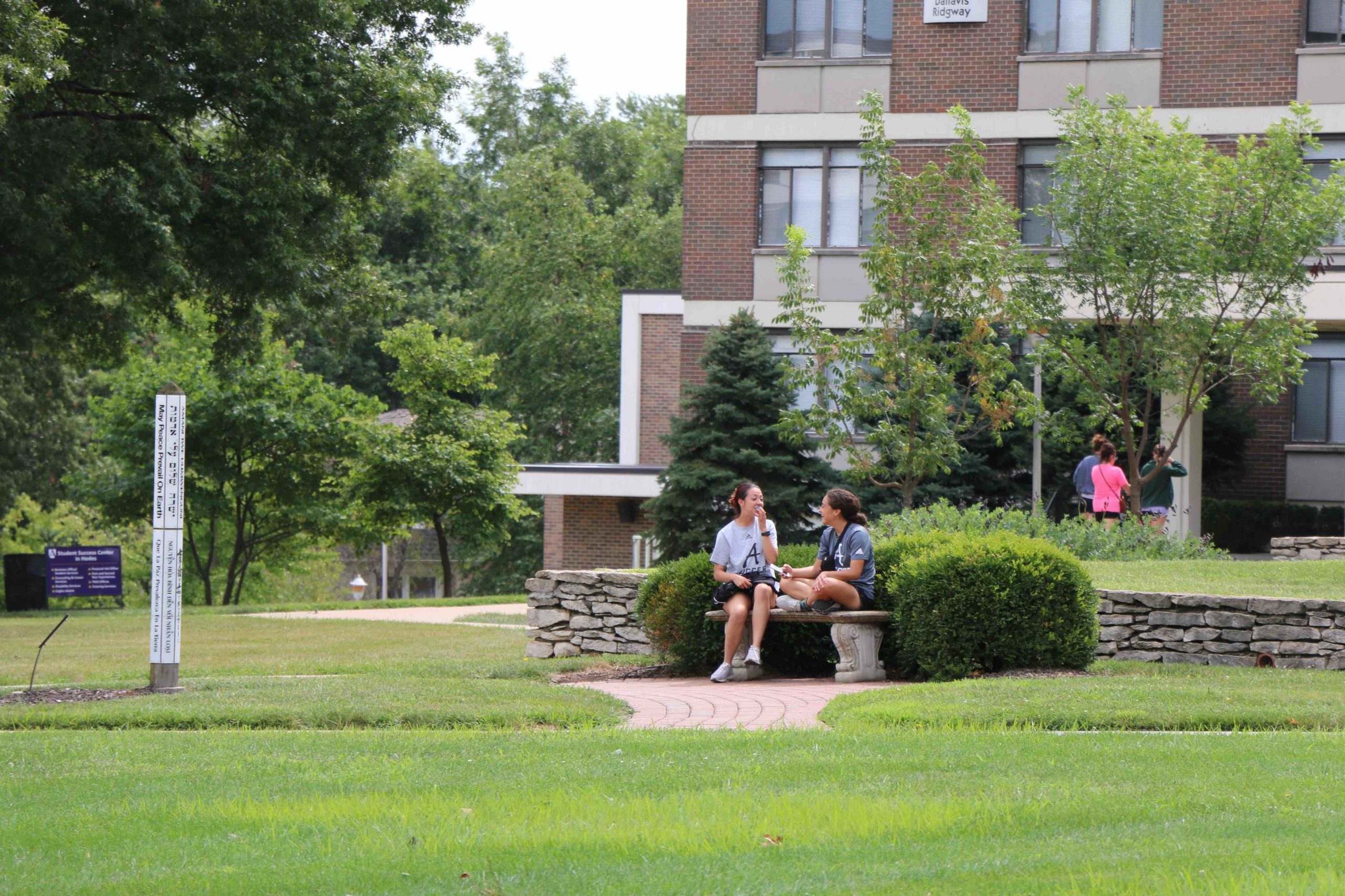两个学生坐在福伊尔大厅前的长凳上聊天