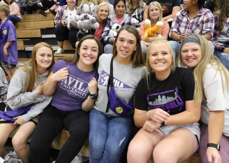 A group of five students pose on the bleachers inside Mabee Fieldhouse
