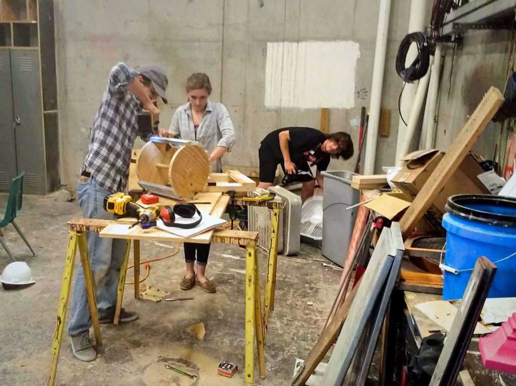 Three students working inside the scene shop