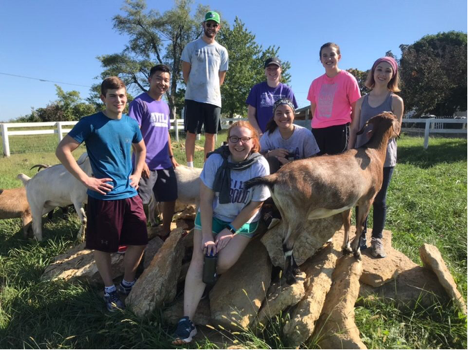 Eight student posing with goats at Boys Grow farm