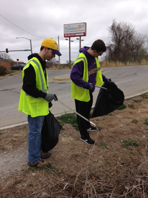 Two students picking up trash along the roadside