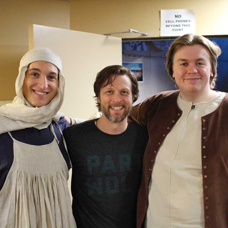 Three Avila students and faculty standing back stage at theatre production