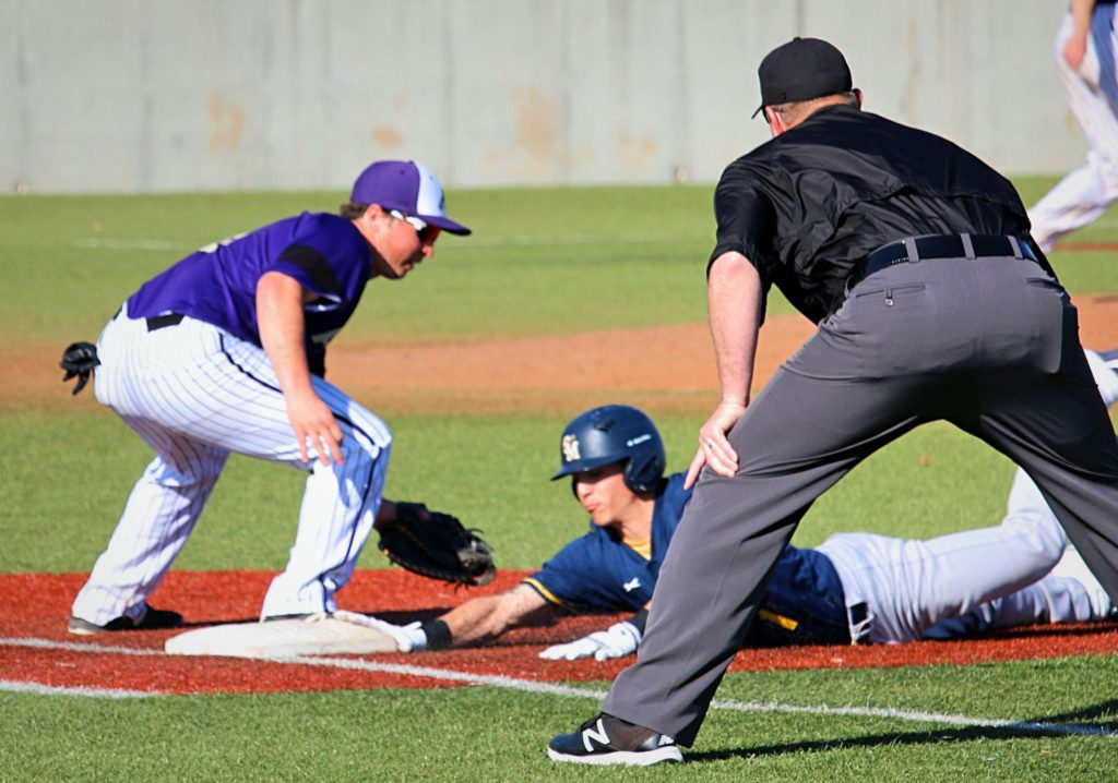 Base runner sliding back to first base in pick off attempt