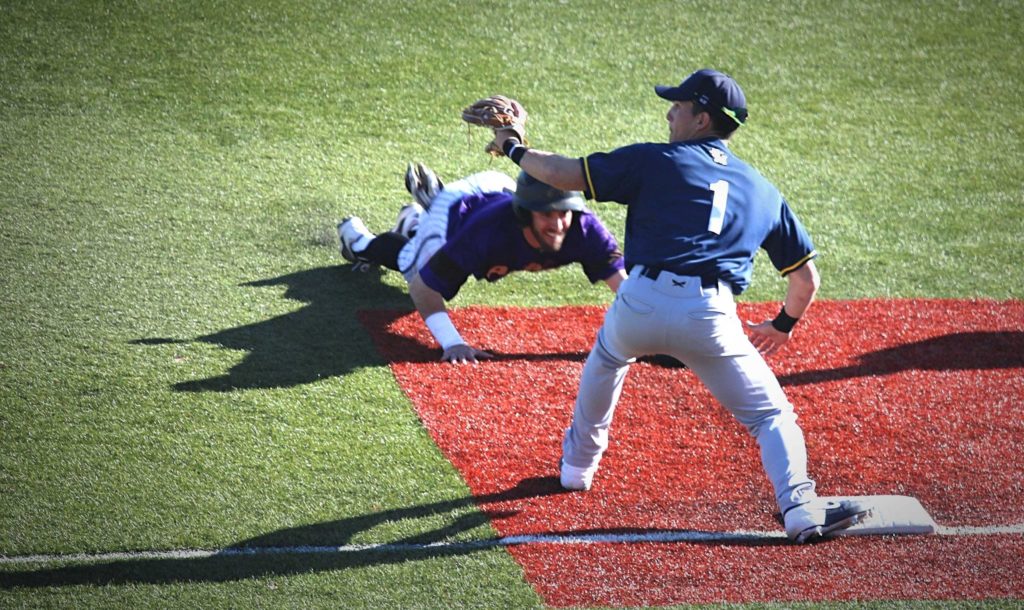 Avila players sliding head-first into third base to beat the tag