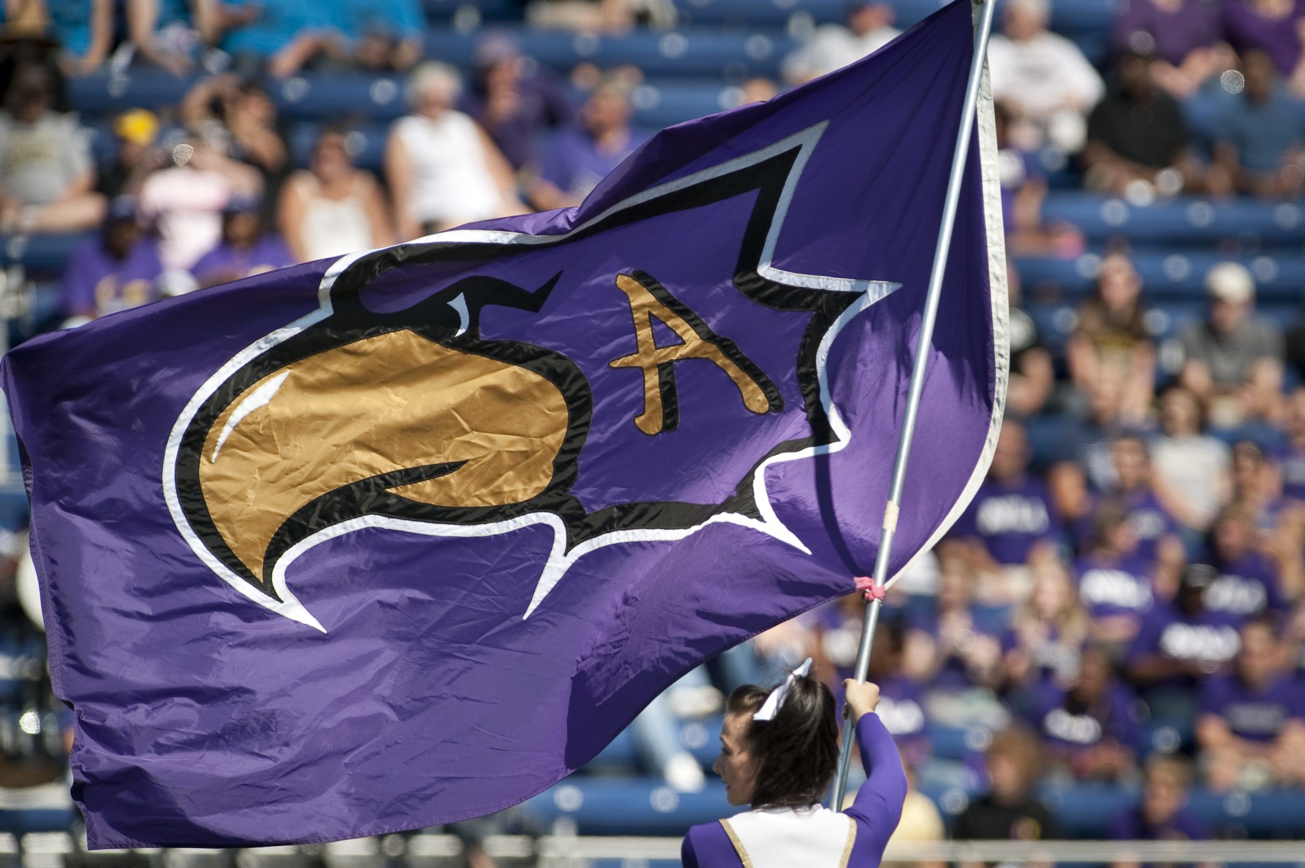 Avila University Eagle logo flag being waved at football game by cheerleader