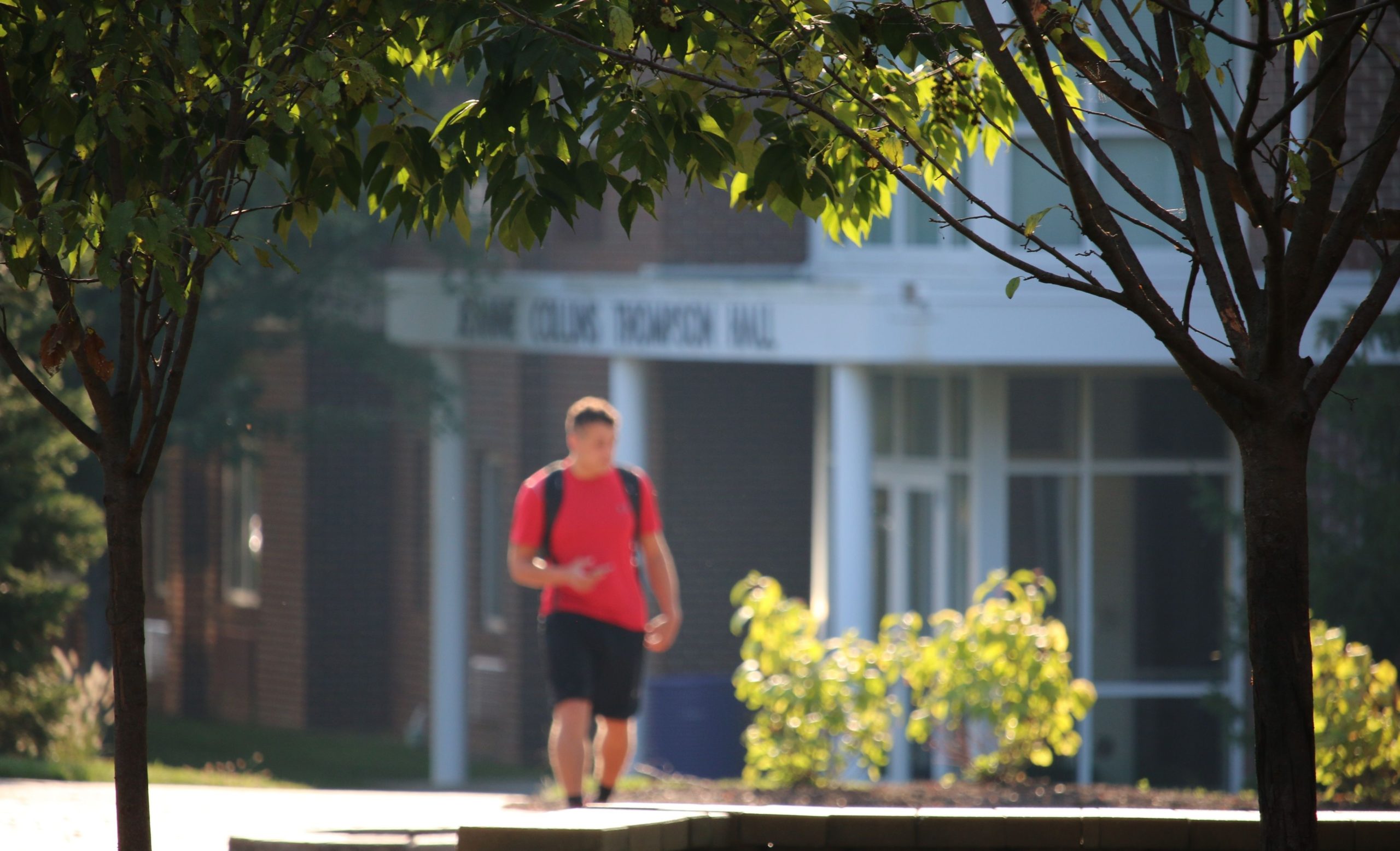 Male student walking in front of Thompson Hall
