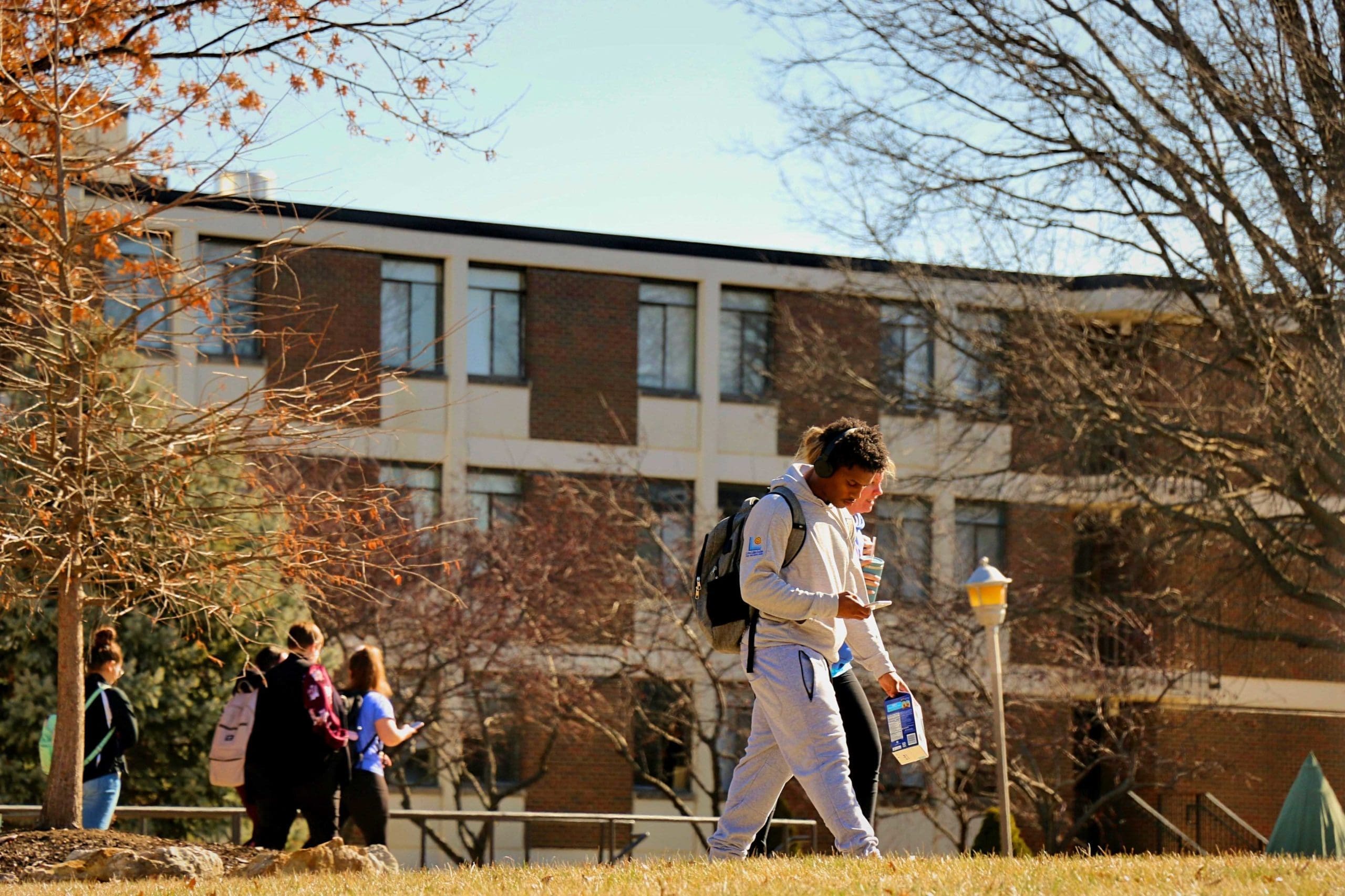 Two students walking in front of Carondelet Hall in the fall