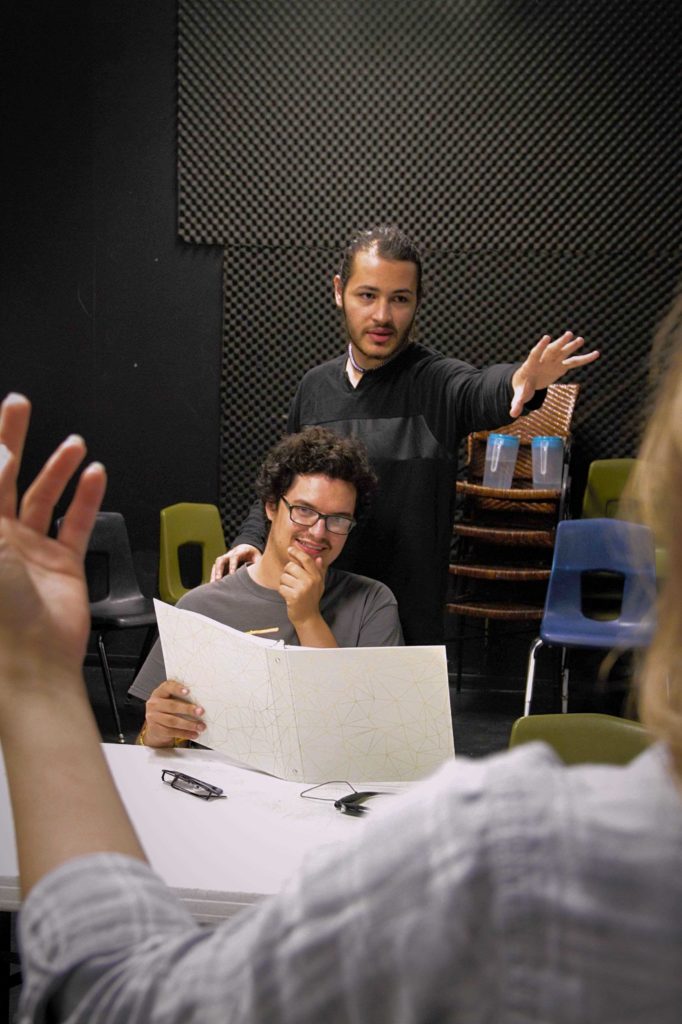 Two students in the theatre rehersal room directing a third student