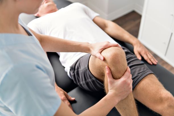 physical therapist with patient manipulating a knee