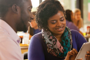 Two adult students sharing an iPad while seated in the dining hall.