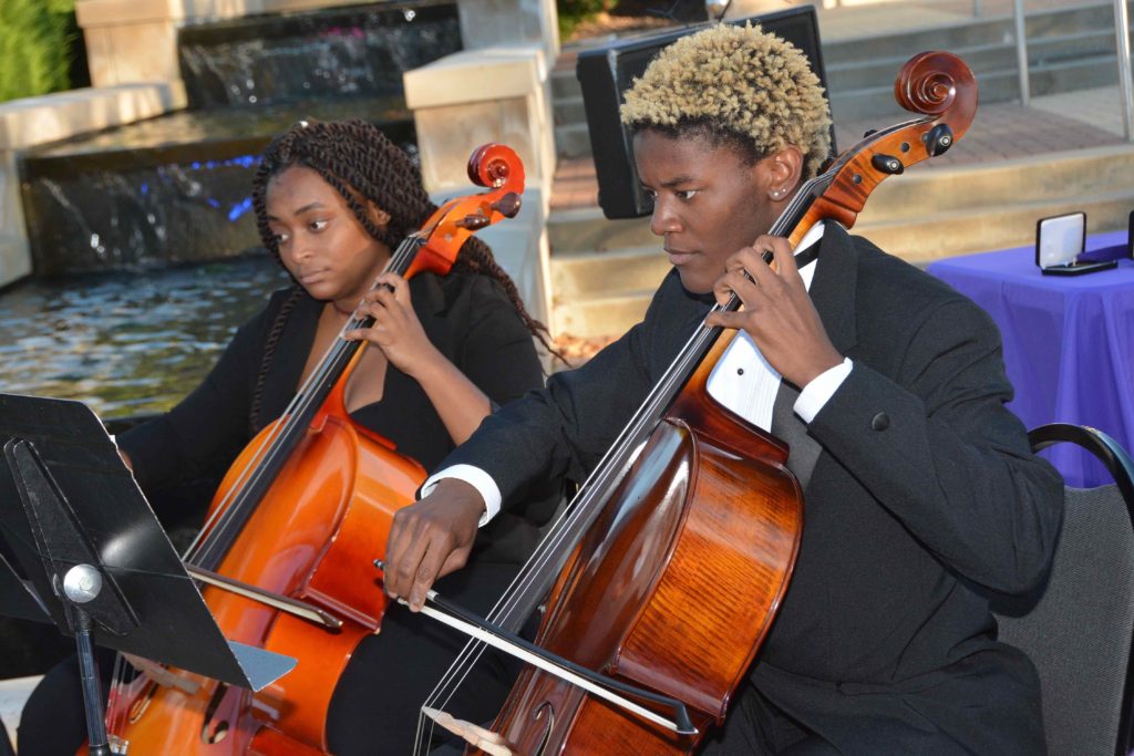 Two Avila cellos players perform outside Blasco Hall
