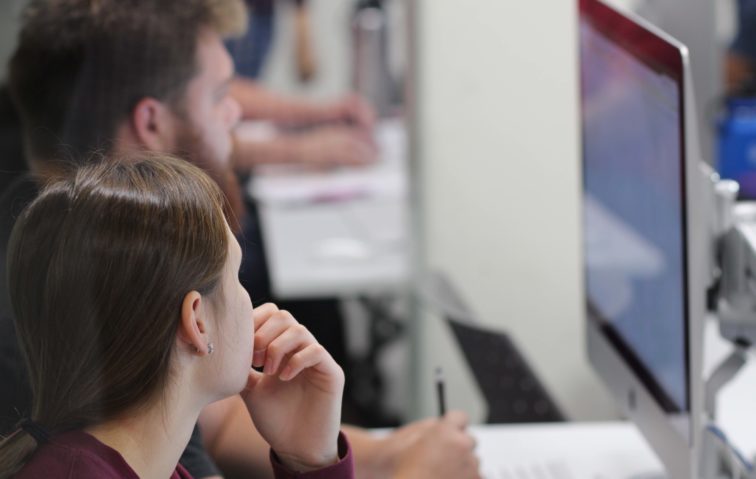 Two students working closely at a computer