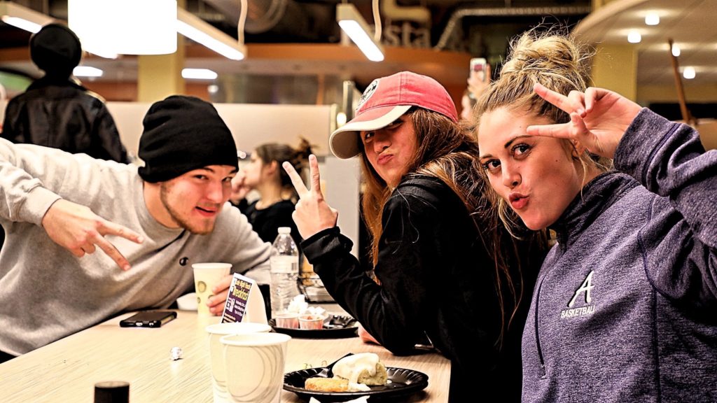Three students posing inside the Marian Center dining hall