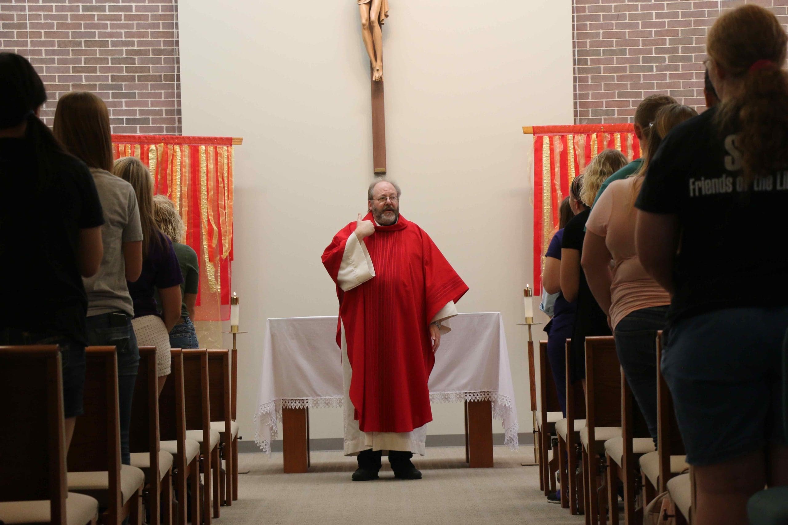 Father Keith Branson in front of student congregation inside Foyle Hall chapel