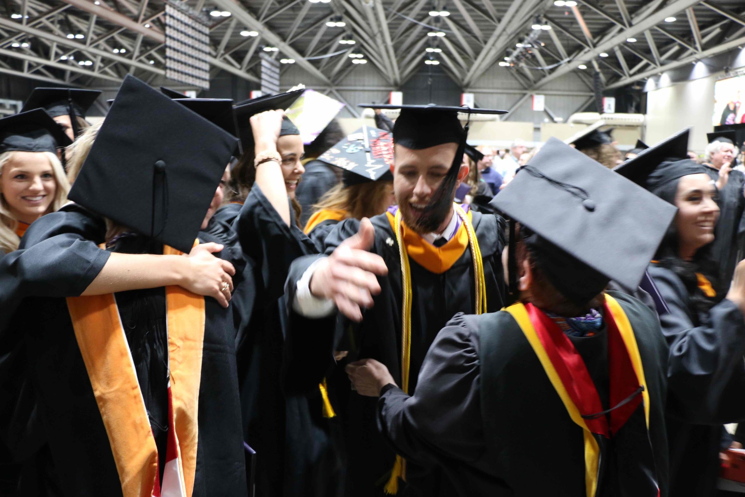 A group of students hugging in the reception line post-graduation