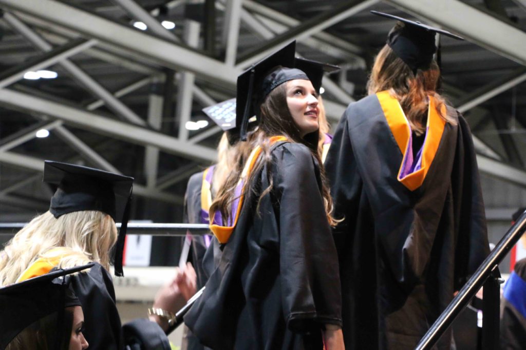 A graduate looks over her shoulder as she walks up the stairs to the commencement stage