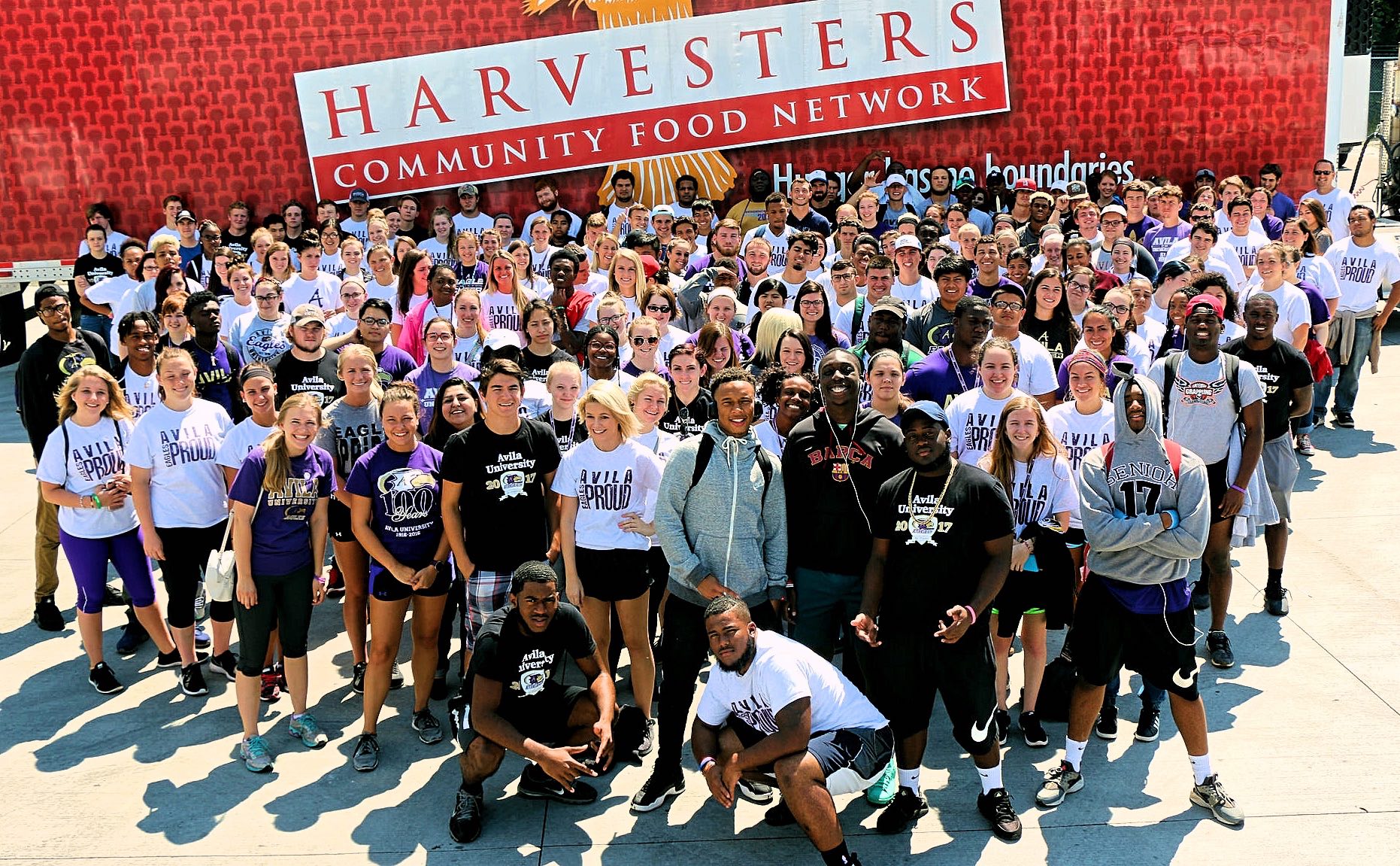 Large group of first year students standing in front of a Harvesters Community Food Network semi-trailer.
