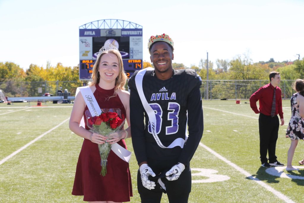 Homecoming Queen and King posing on the football field during halftime