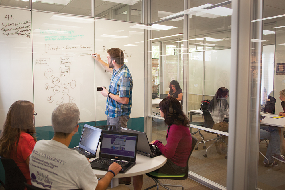 Adult students inside the Learning Commons with a whiteboard behind
