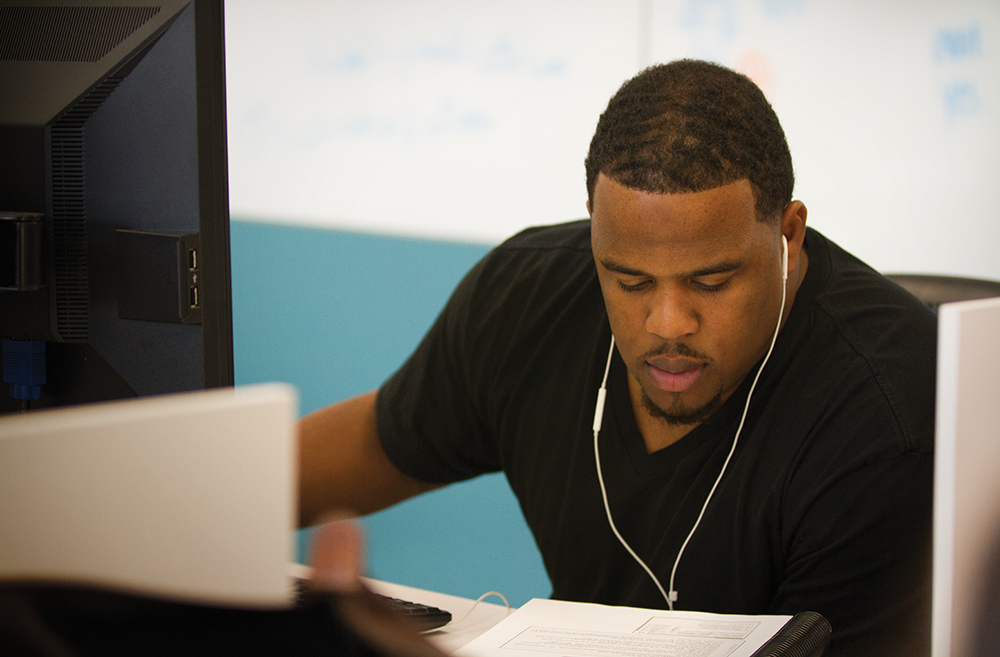 Male student working on a computer wearing ear phones
