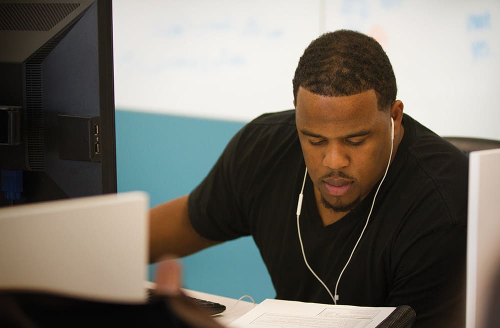 Male student working on a computer wearing ear phones