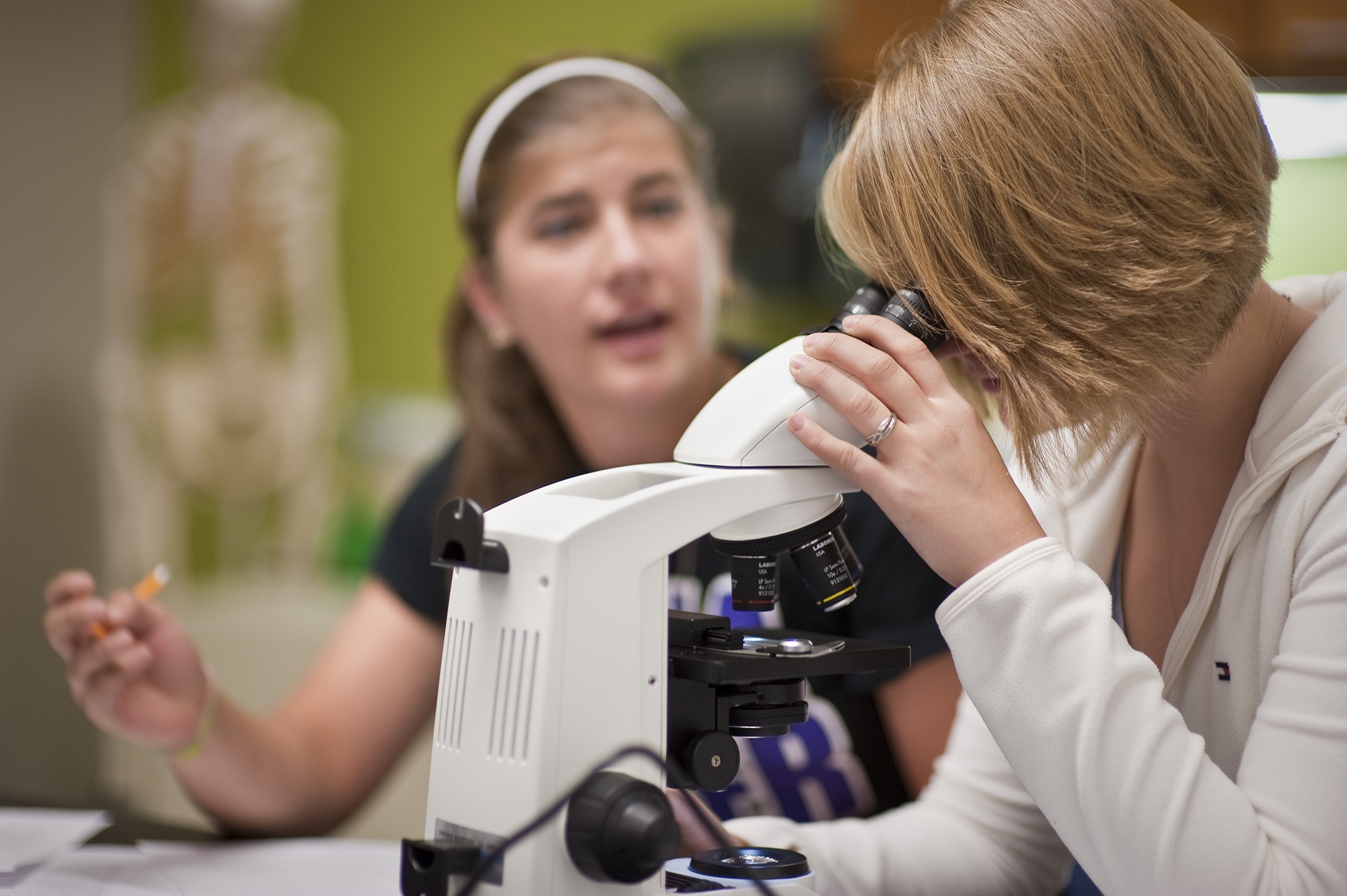 Two students collaboratively working with a lab microscope