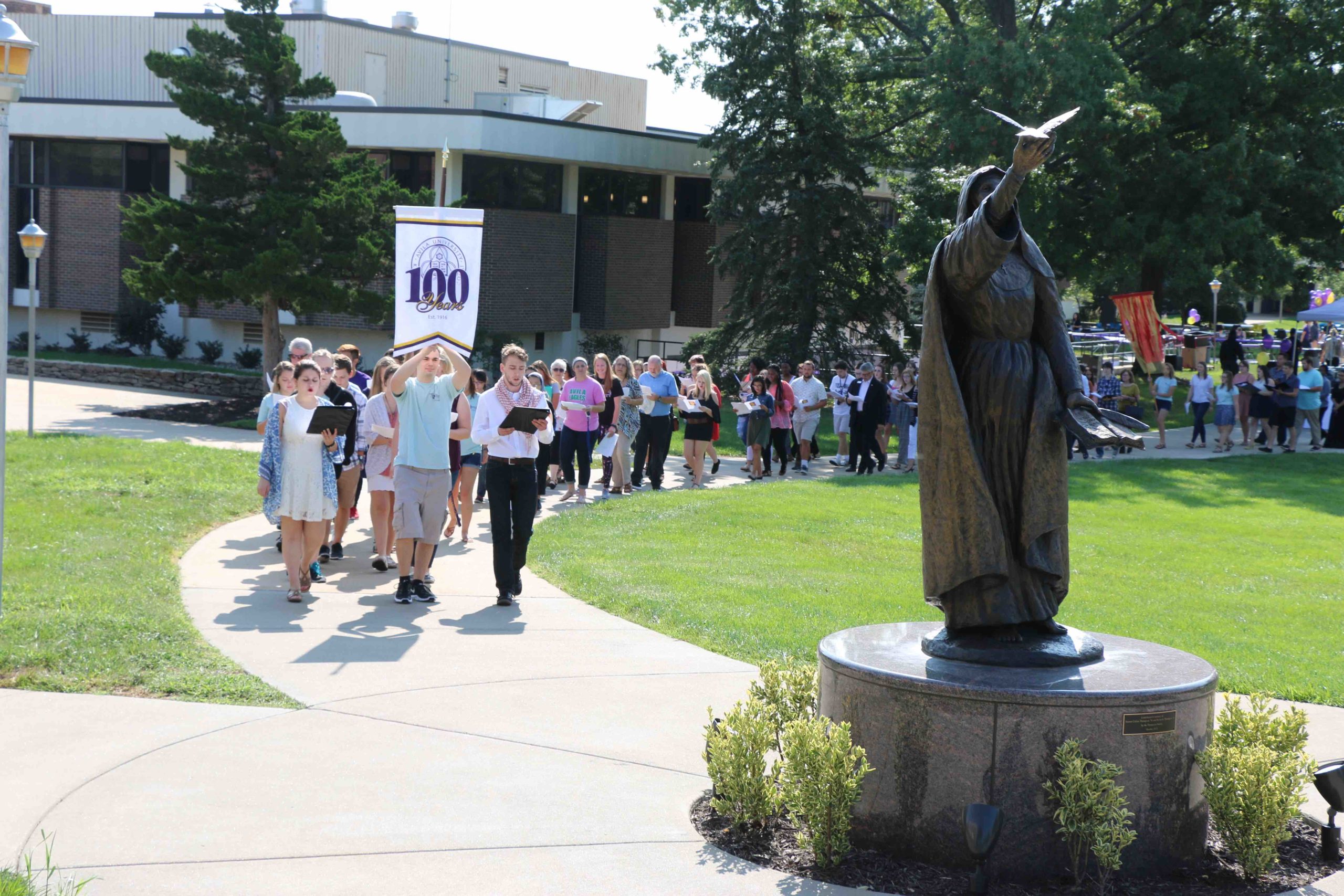 The Avila community marches across campus together in a long line promoting peace.