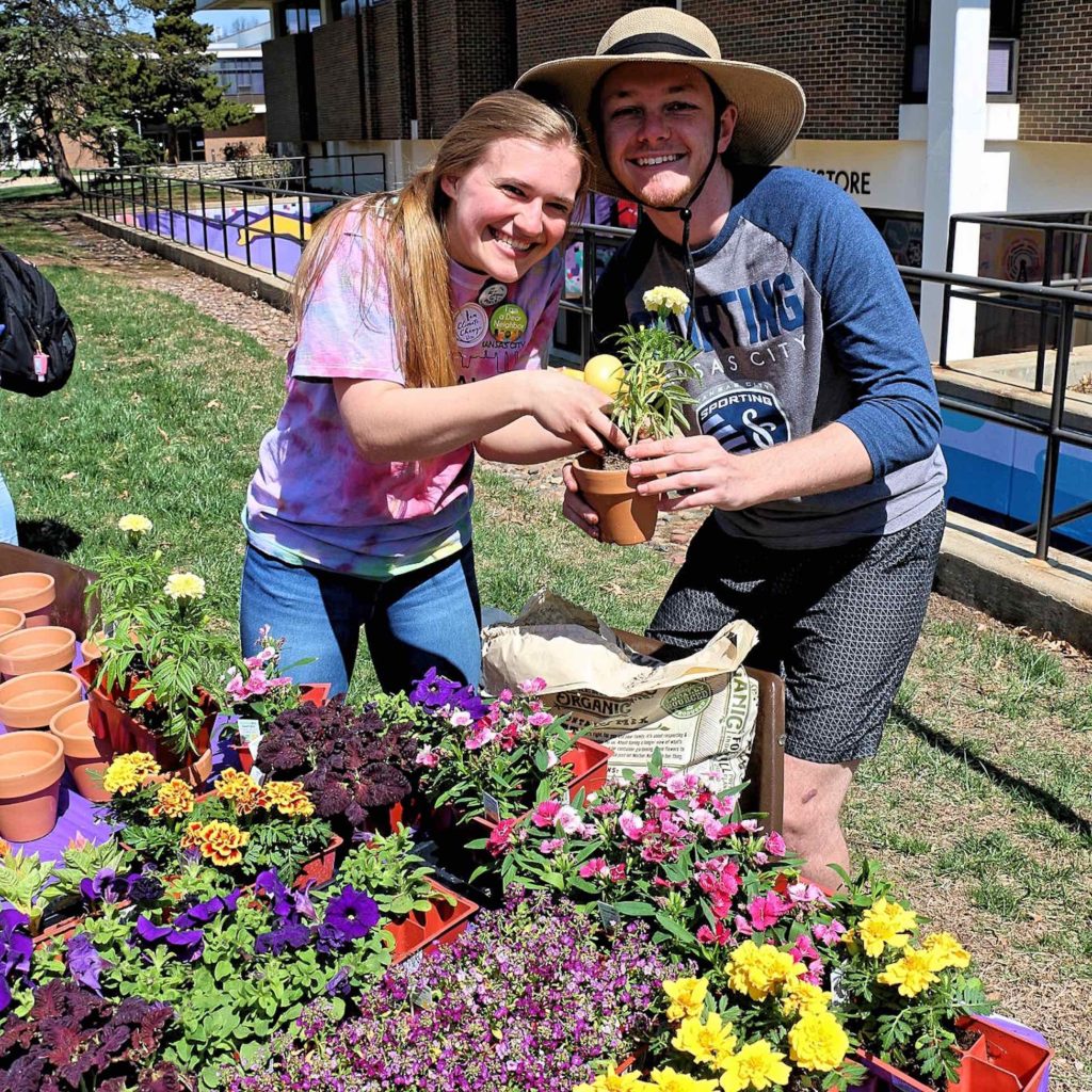 Two students working the potted plant table during a campus carnival