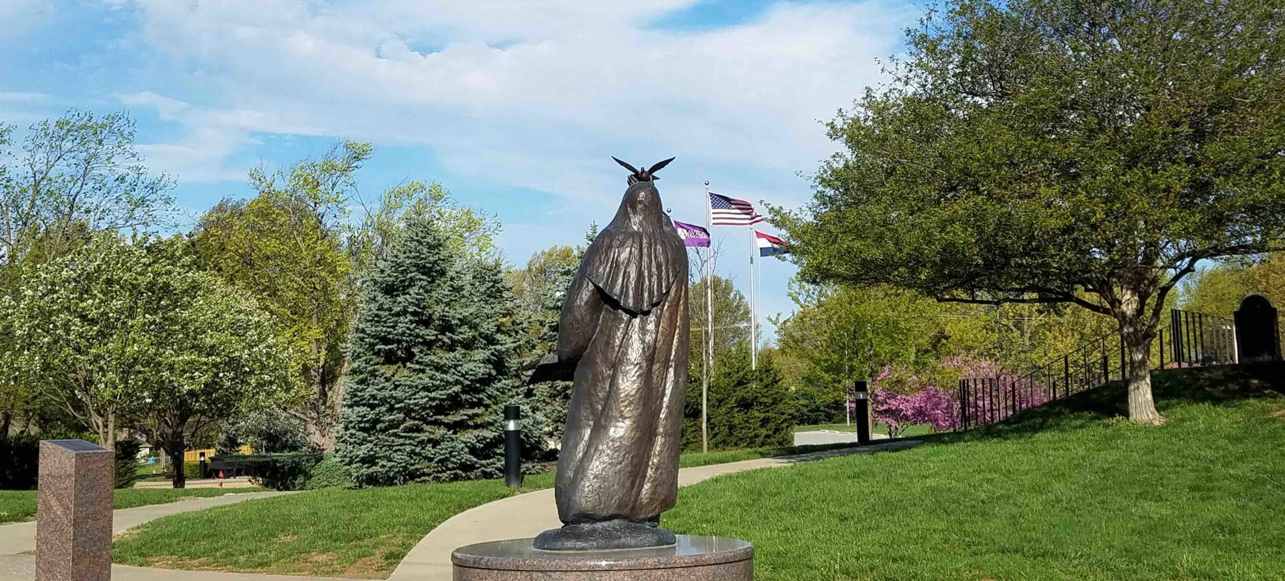 Statue of St. Teresa of Avila on campus with flag poles in the background