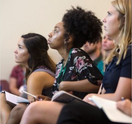 Three students taking notes in class