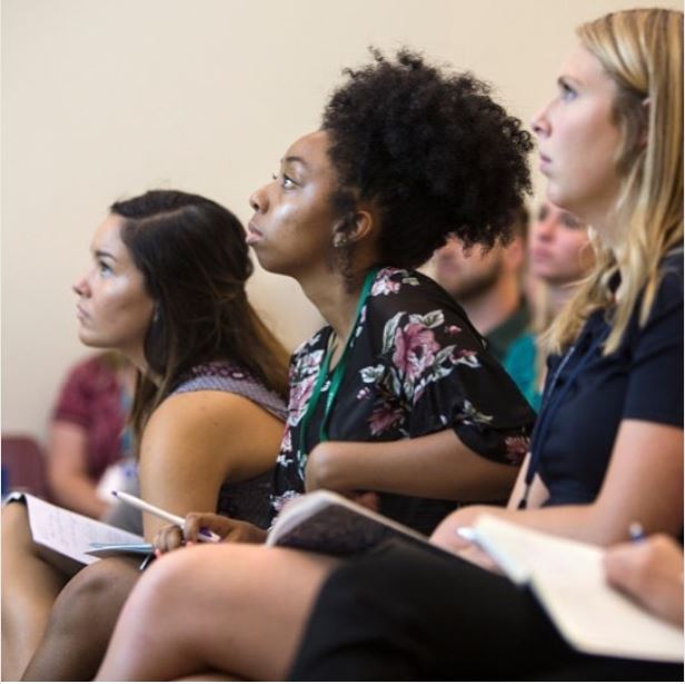 Three students taking notes in class