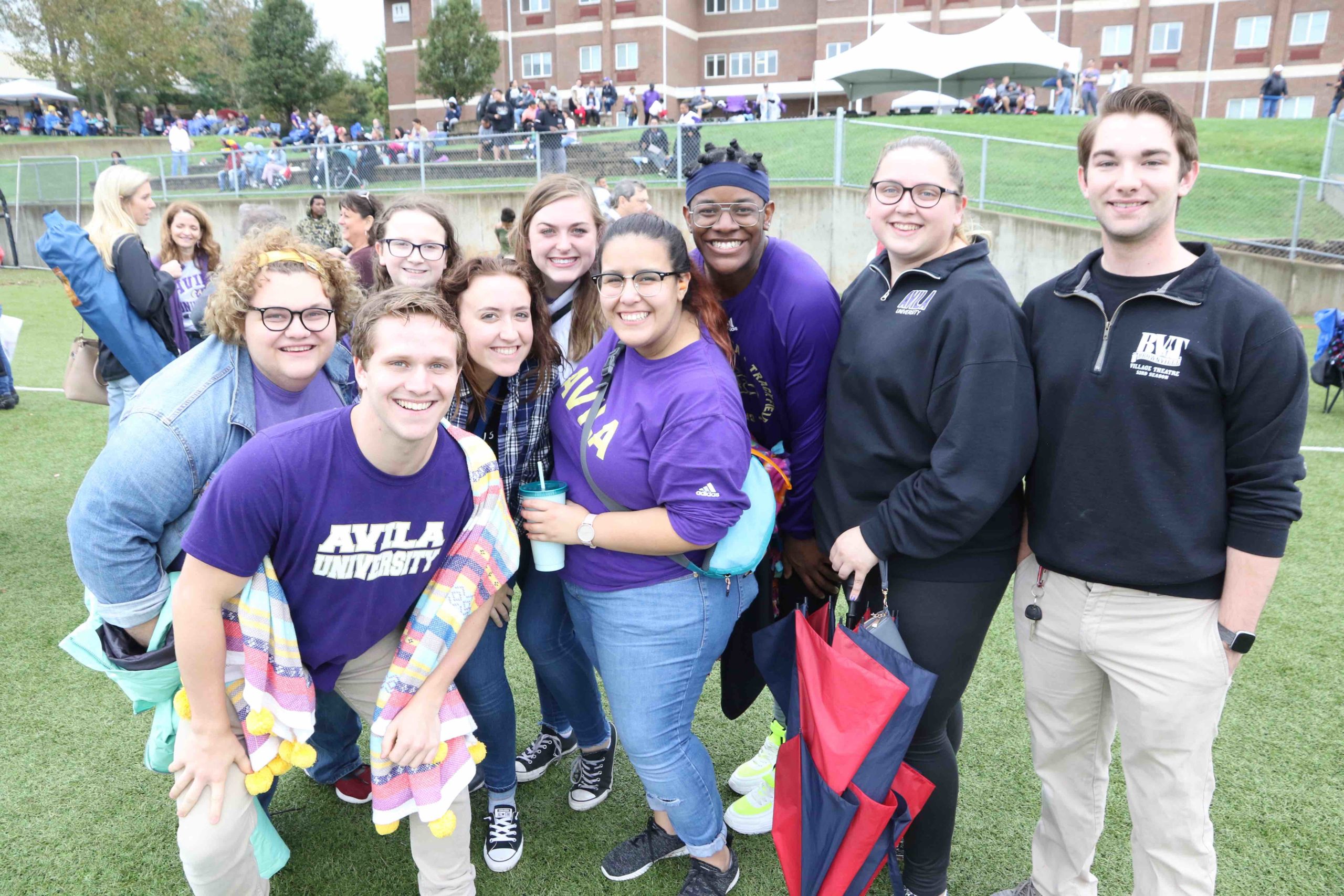 A group of students pose for the camera while standing on the football sidelines
