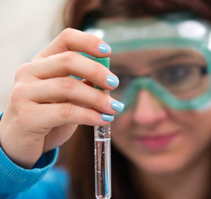 Close up of a student holding a test tube holding a clear liquid