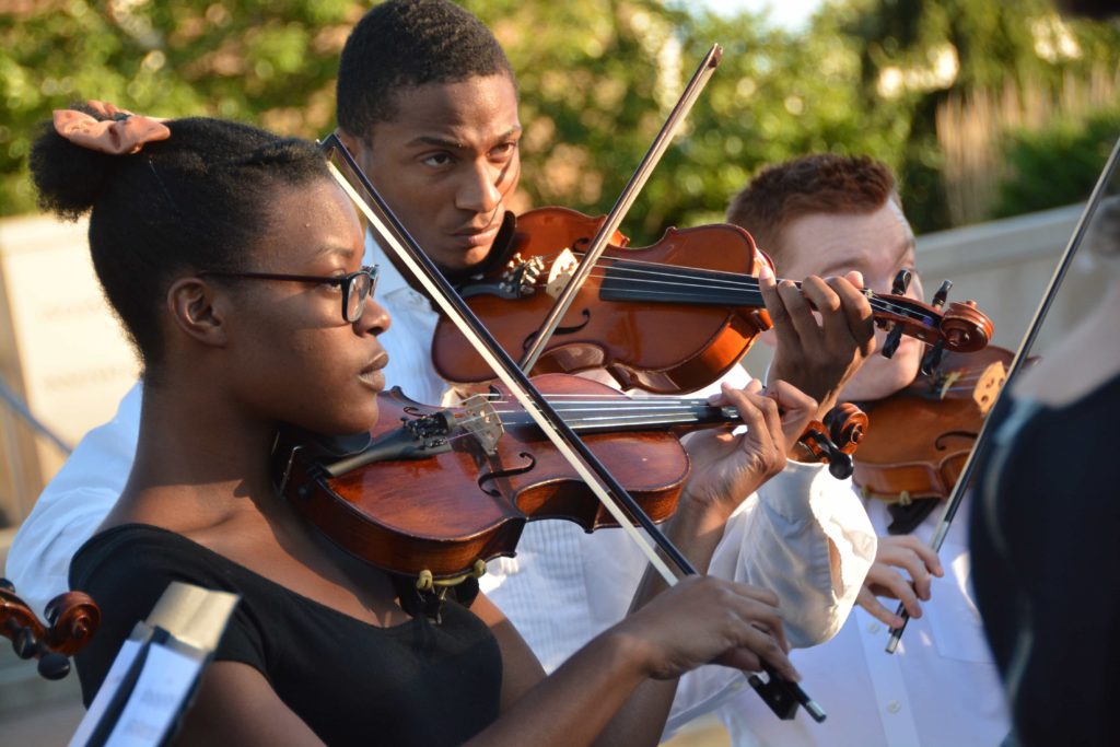 Close up of three stings performers in close up during a homecoming event.