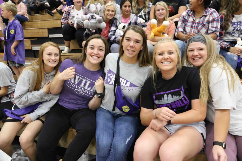 A group of five students pose on the bleachers inside Mabee Fieldhouse