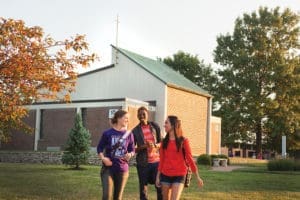 Wider shot of three student walking toward the camera with Foyle Hall in the background