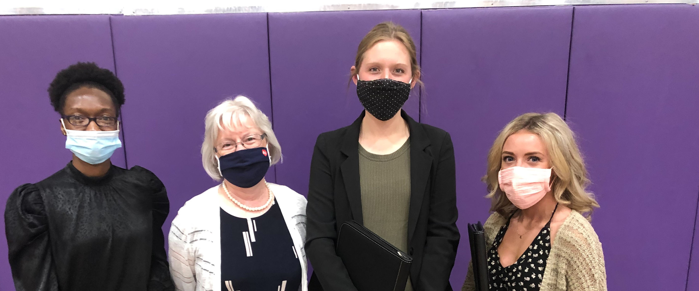 Four women posed in-line with masks on