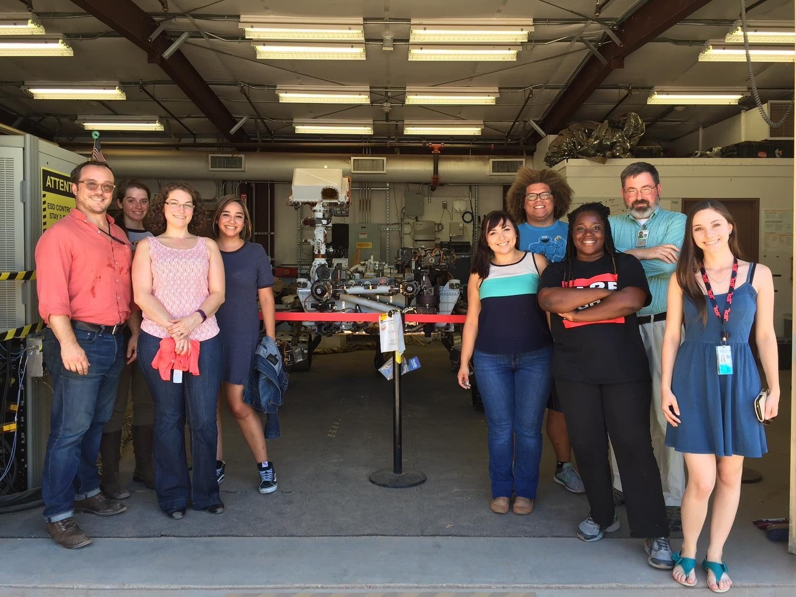 Group of men and women pose around Mars rover