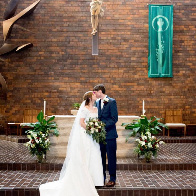 Photo of bride and groom kissing at altar