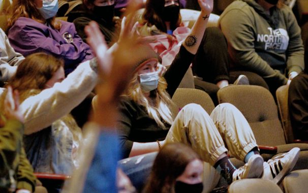 Students raising their hands to answer questions during a lecture inside Goppert Theatre