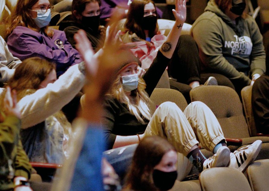 Students raising their hands to answer questions during a lecture inside Goppert Theatre
