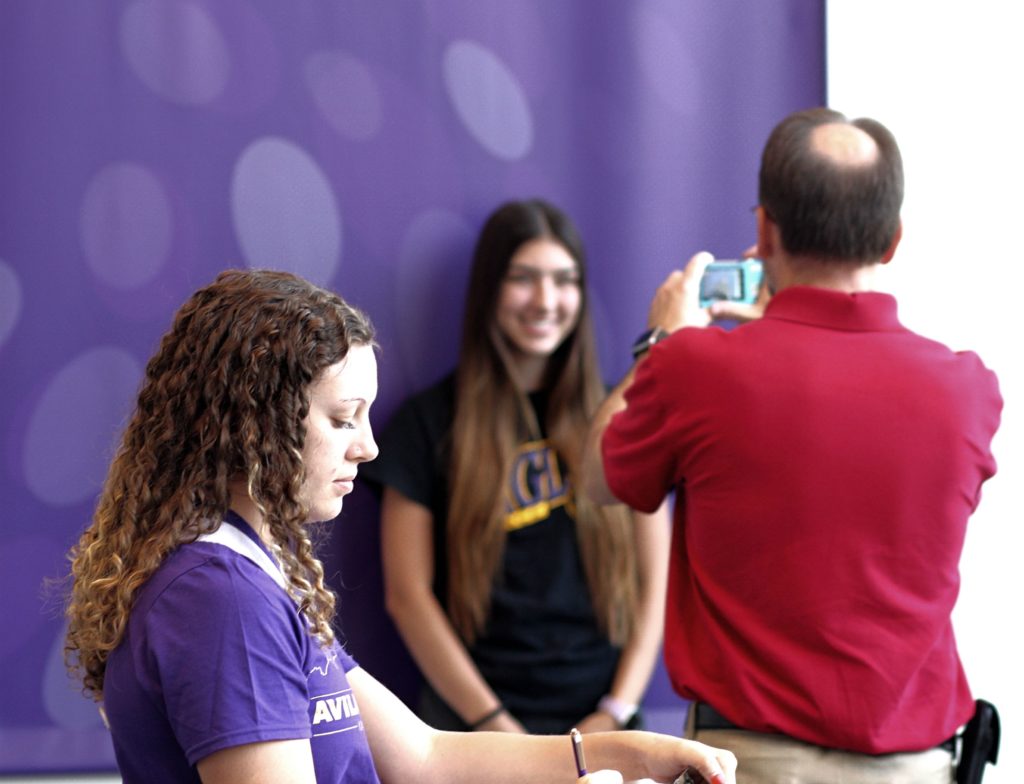 Admission rep in the foreground while campus safety takes a student's photo for her ID card